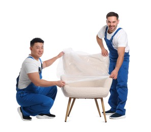 Photo of Workers covering armchair with plastic film on white background
