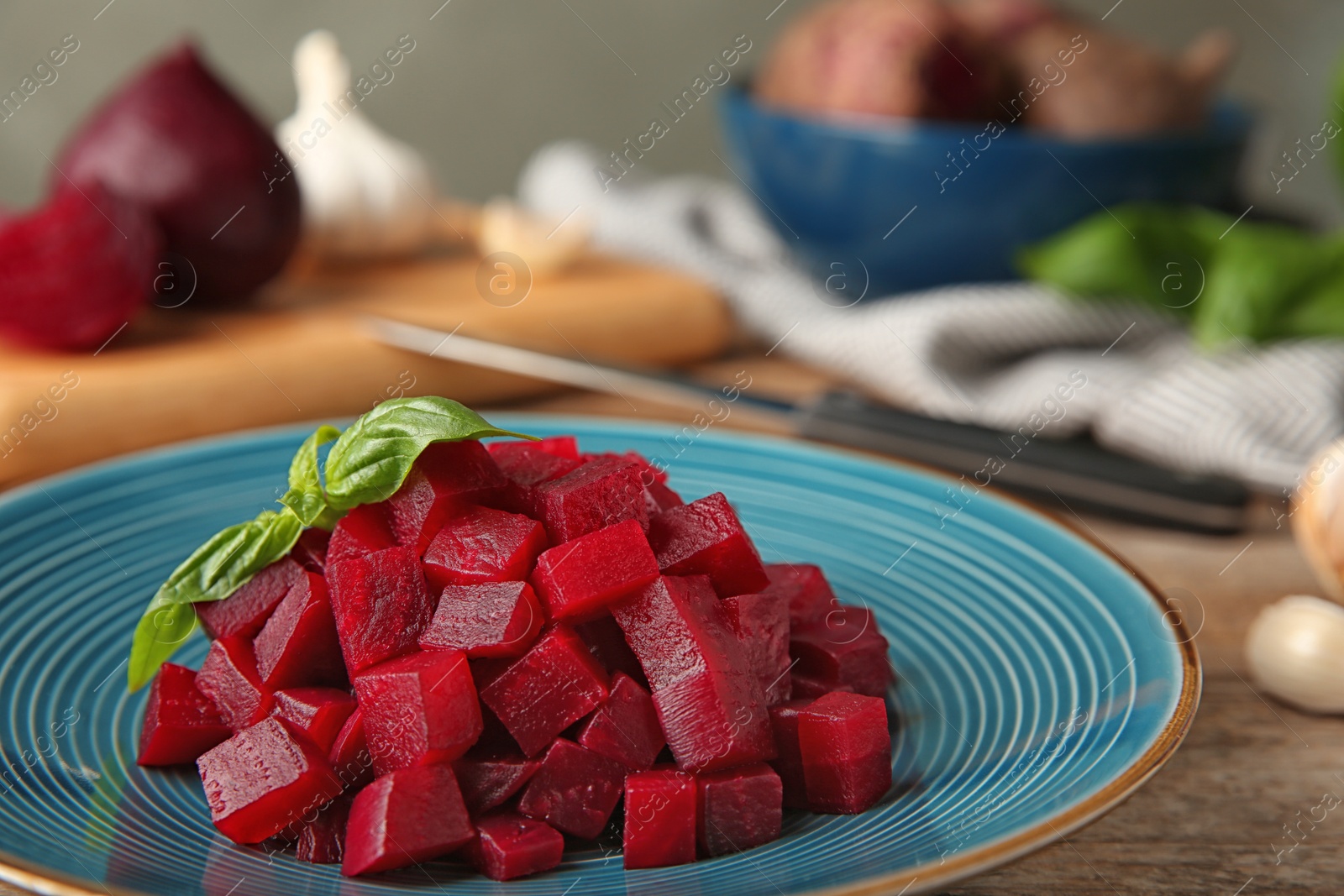 Photo of Plate of cut boiled beets with basil on wooden table, closeup