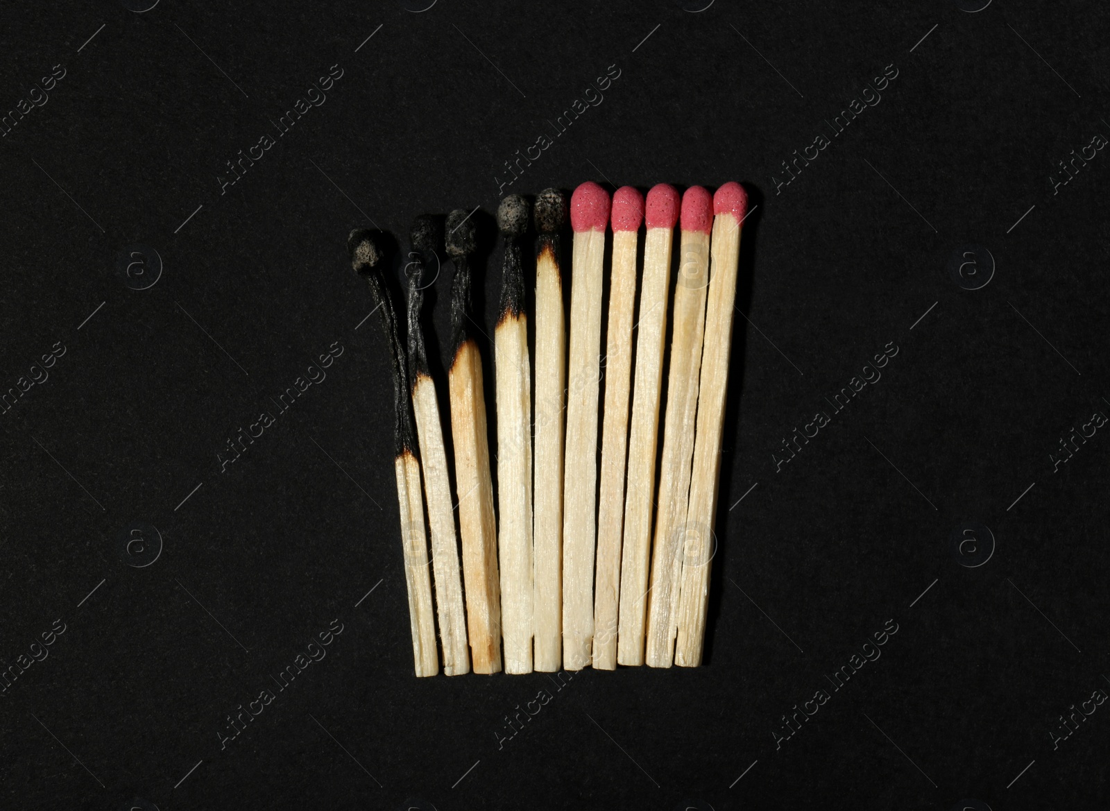 Photo of Burnt and whole matches on black background, flat lay. Stop destruction concept