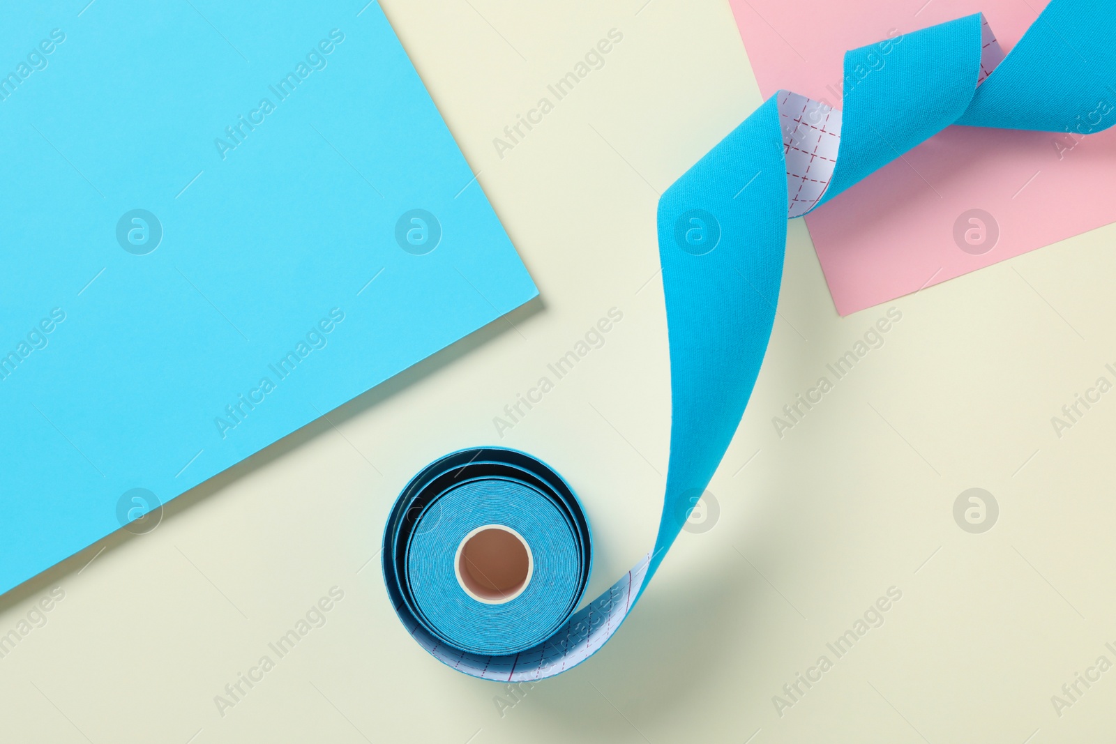 Photo of Bright kinesio tape in roll on color background, top view