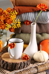 Beautiful autumn composition with cup of drink and pumpkins on wicker table