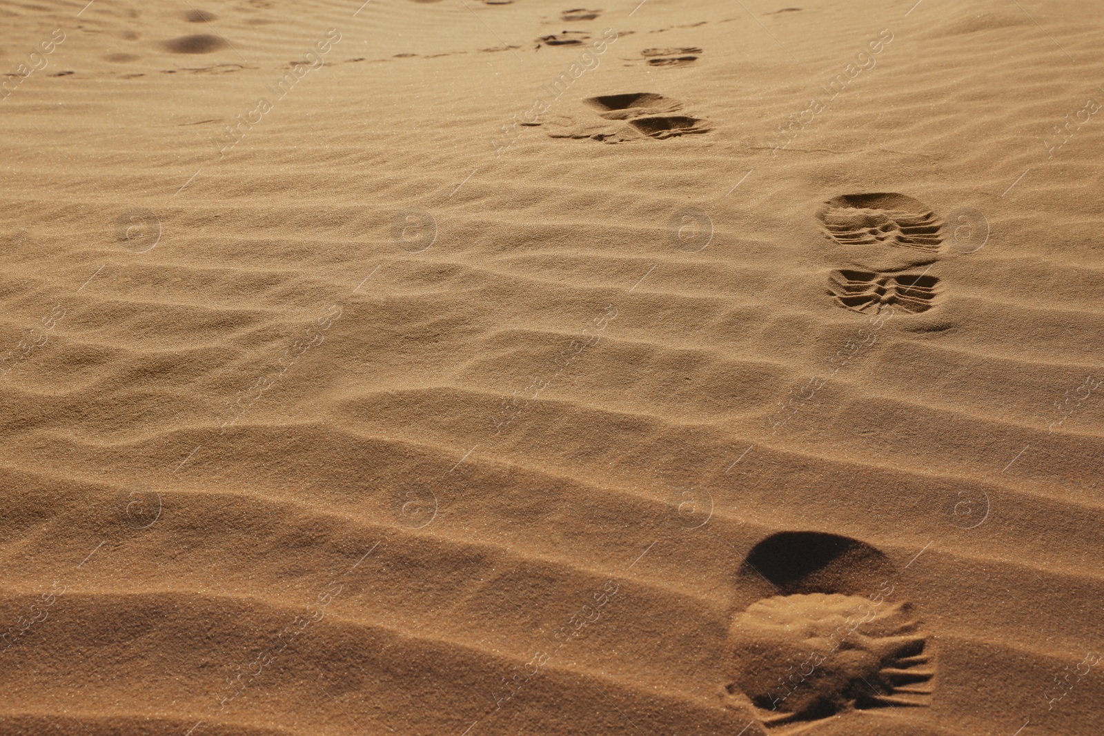 Photo of Trail of footprints on sand in desert