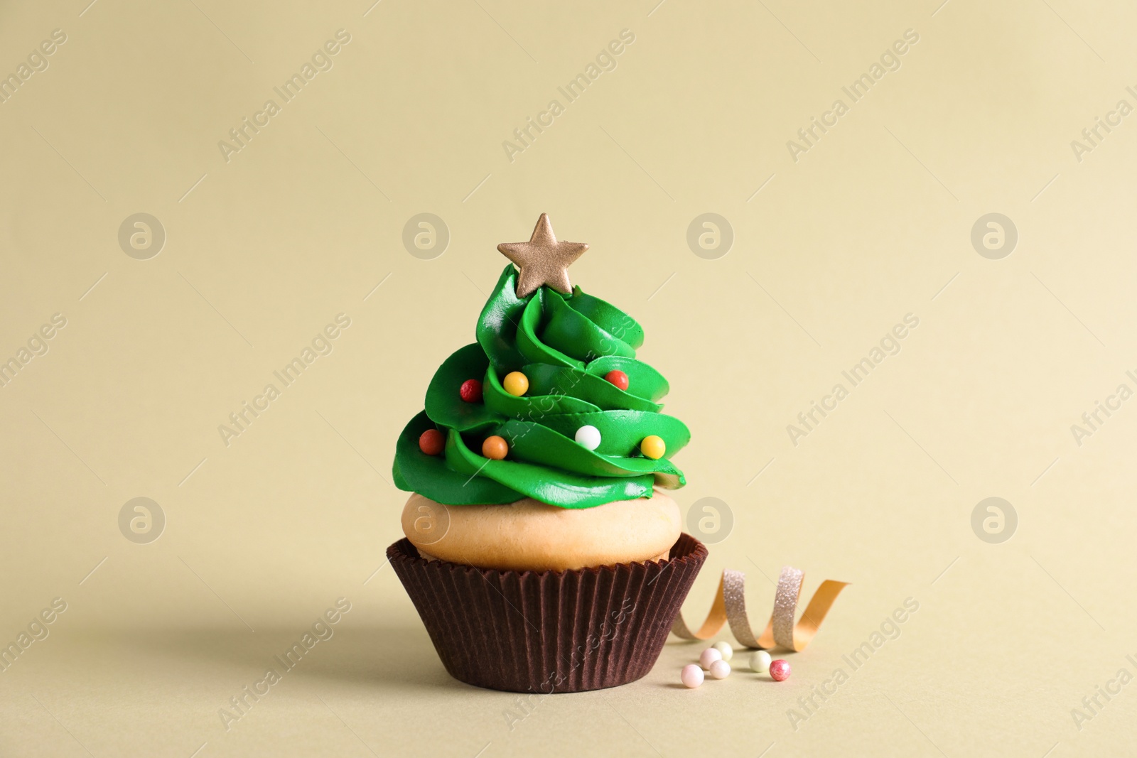 Photo of Christmas tree shaped cupcake and streamer on green background