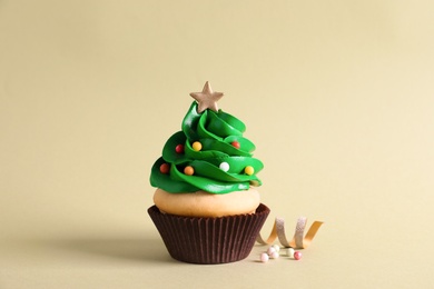 Christmas tree shaped cupcake and streamer on green background