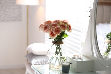 Photo of Glass vase with beautiful flowers on dressing table in modern room interior