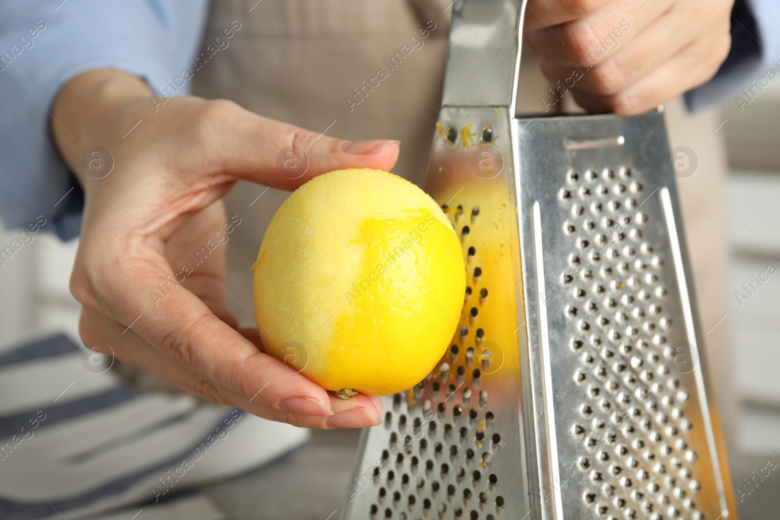 Photo of Woman zesting fresh lemon indoors, closeup view