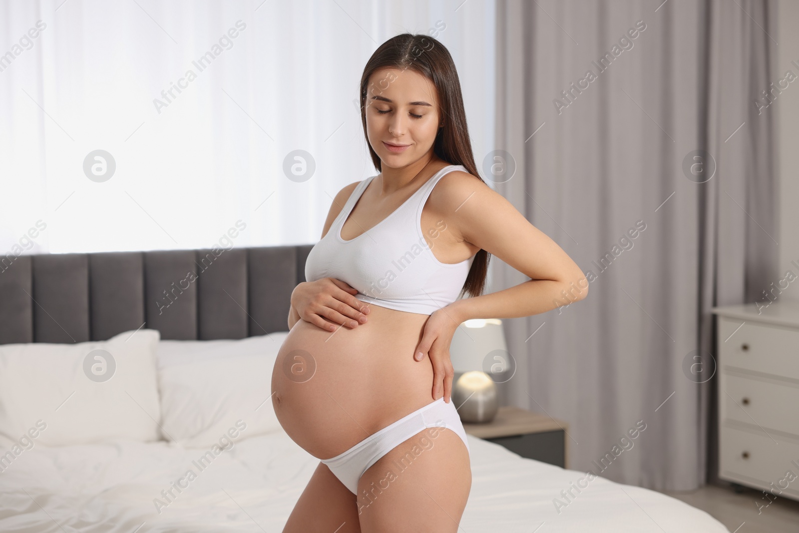 Photo of Beautiful pregnant woman wearing stylish comfortable underwear in bedroom