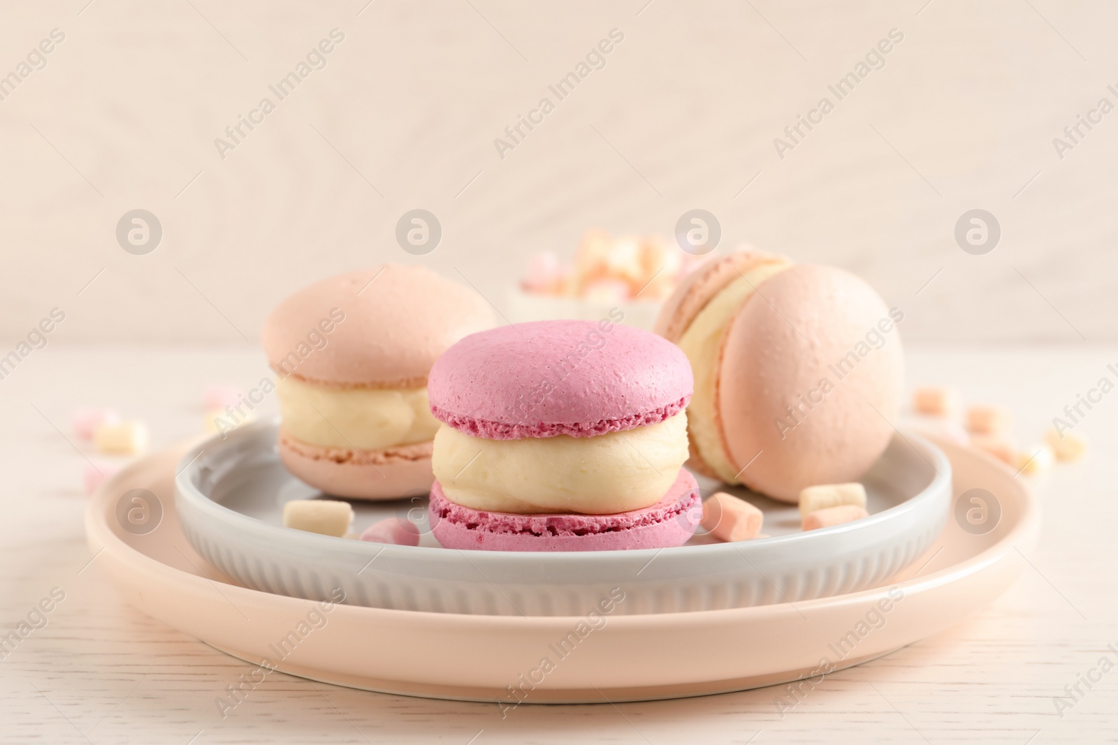 Photo of Delicious colorful macarons and marshmallows on white wooden table, closeup