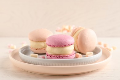 Photo of Delicious colorful macarons and marshmallows on white wooden table, closeup