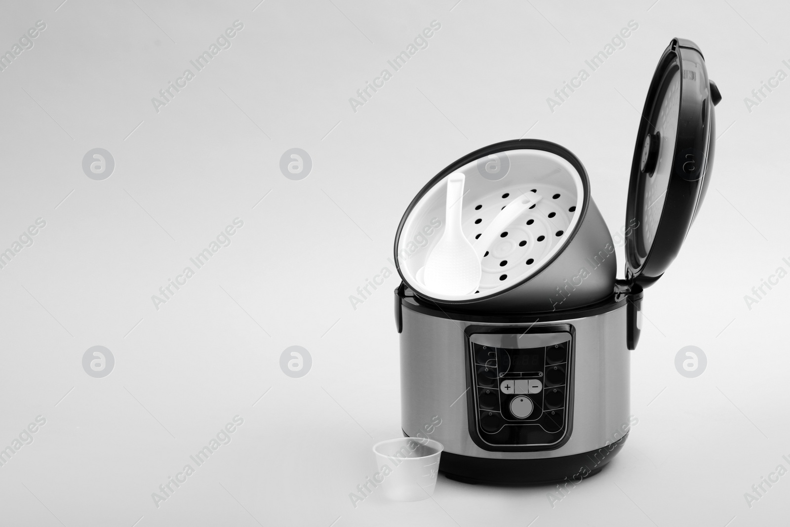 Photo of Modern electric multi cooker, parts and accessories on grey background. Space for text