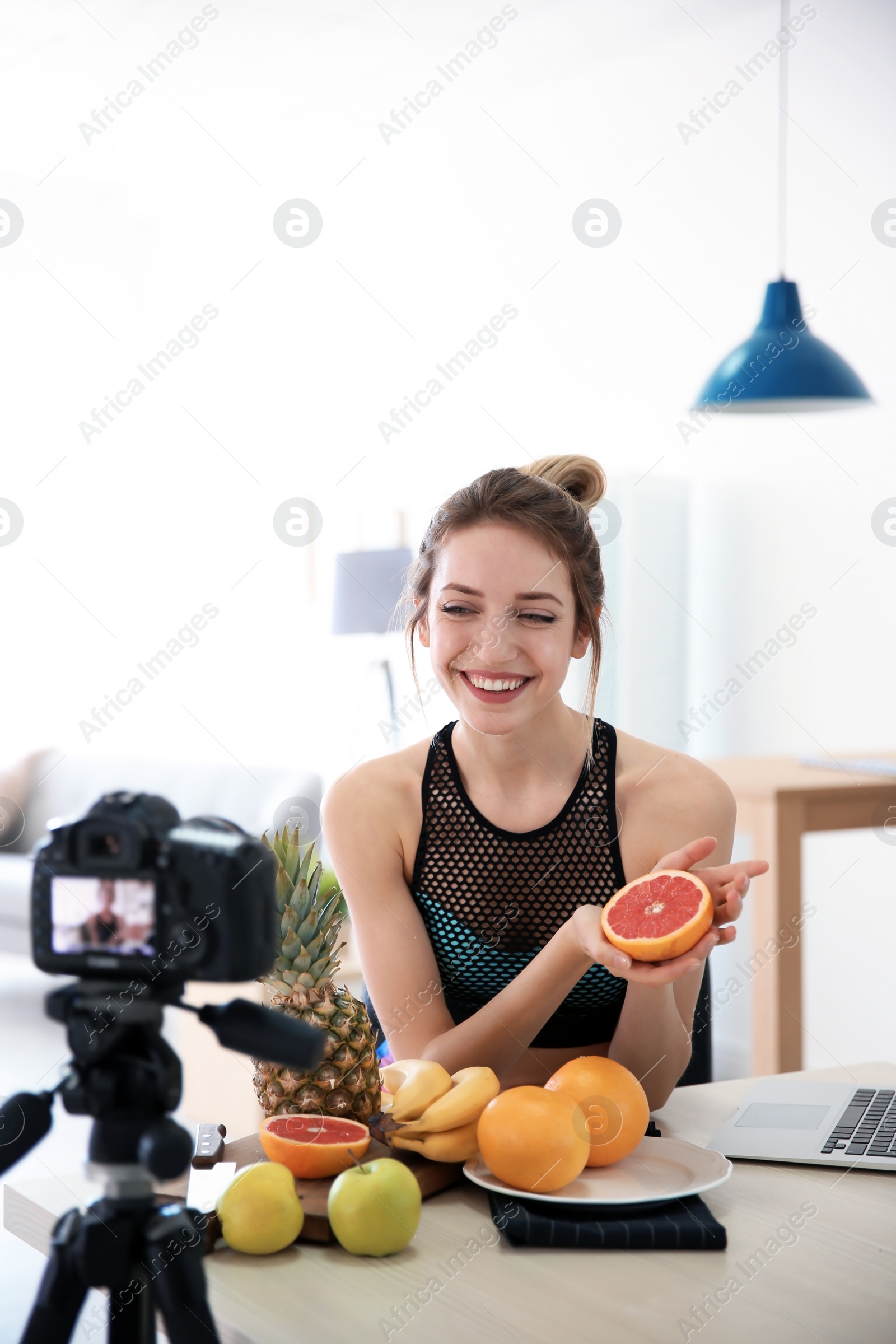 Photo of Young blogger with fruits recording video on kitchen