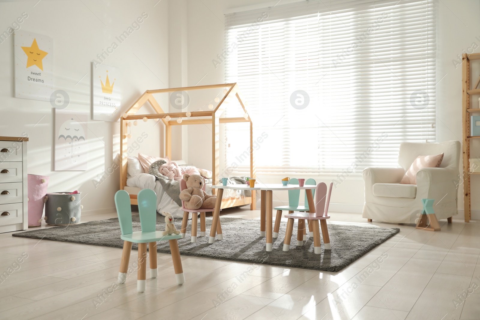 Photo of Small table and chairs with bunny ears in children's bedroom interior