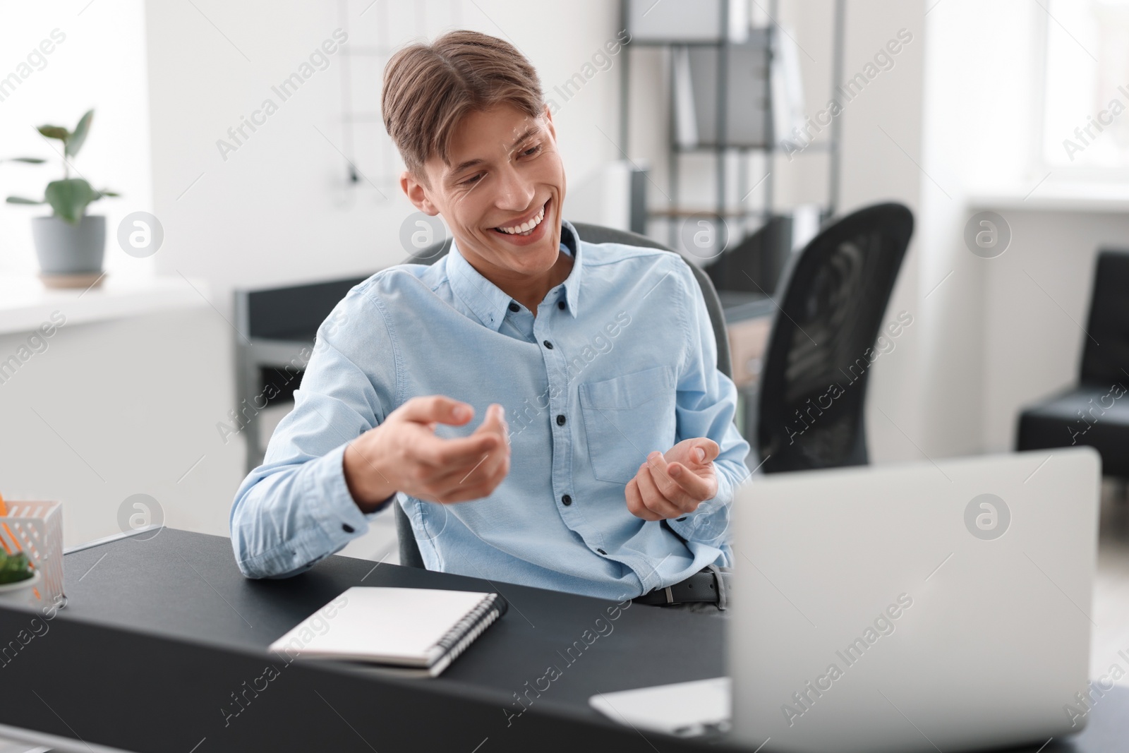 Photo of Man using video chat during webinar at table in office