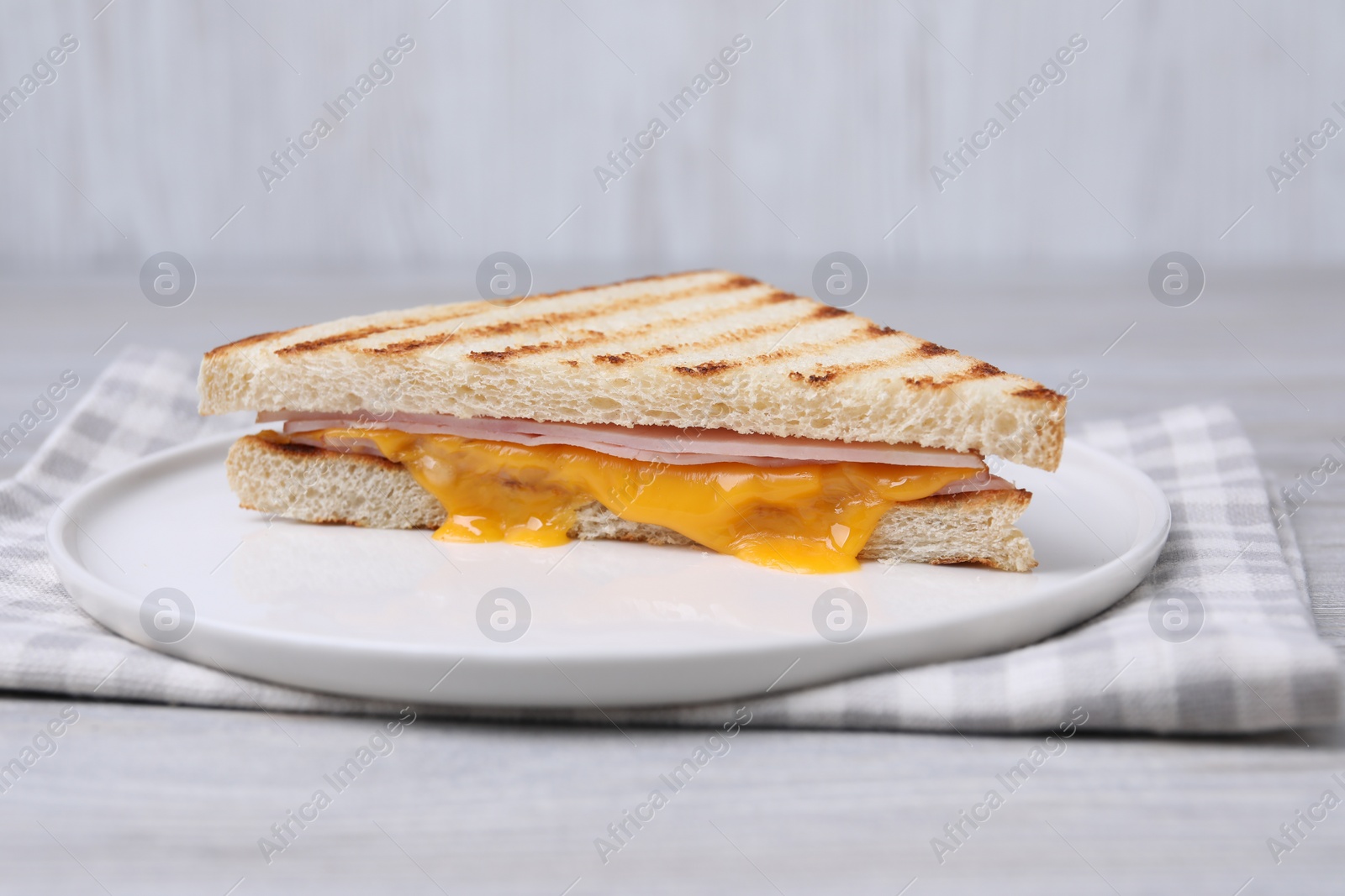 Delicious grilled sandwich with ham and cheese on light table Photo of Delicious grilled sandwich with ham and cheese on light table