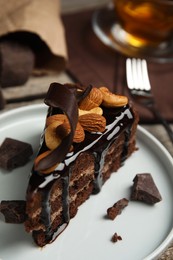 Piece of tasty homemade chocolate cake with nuts on plate, closeup