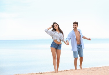 Photo of Happy young couple walking together on beach near sea