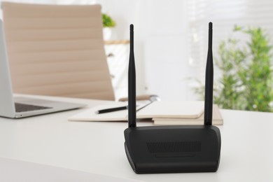 Photo of Modern wi-fi router on white table indoors