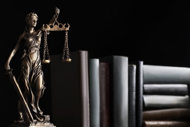 Statue of Lady Justice near books on black background, space for text. Symbol of fair treatment under law