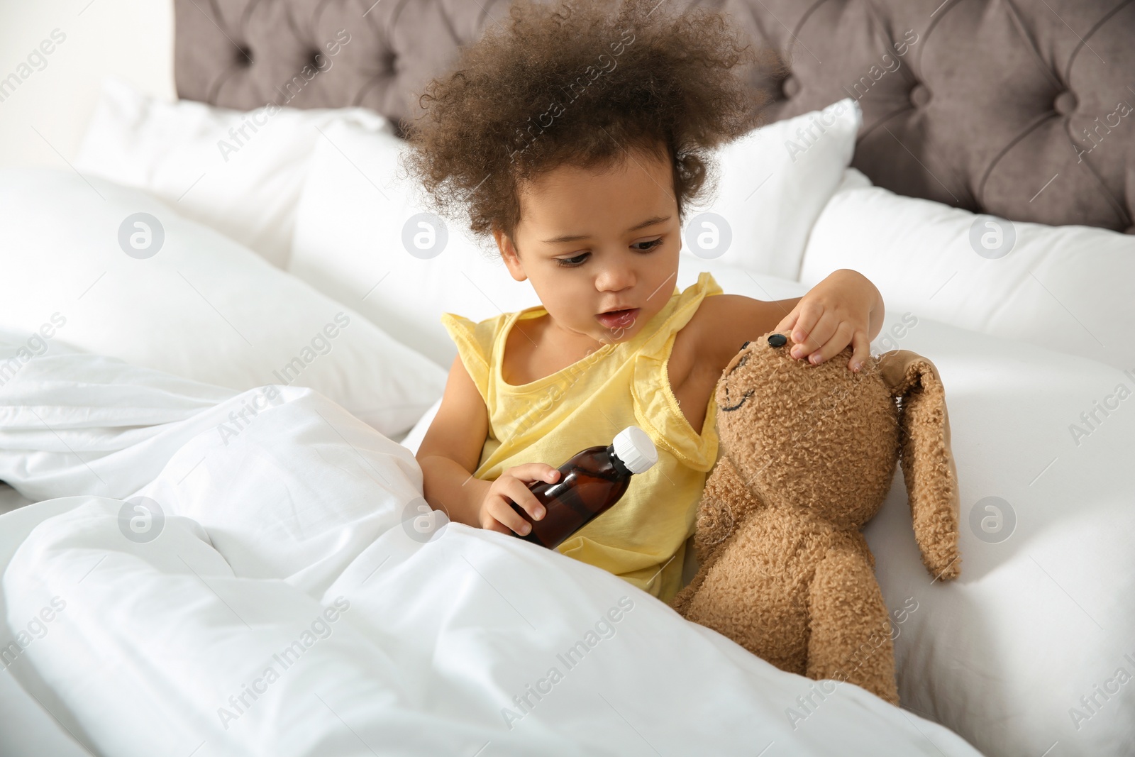 Photo of Cute African American child imagining herself as doctor while playing with toy bunny at home