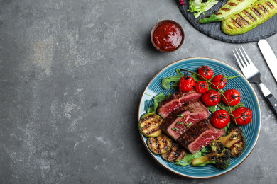 Photo of Delicious sliced beef steak served on grey table, flat lay. Space for text