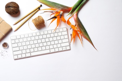 Photo of Creative flat lay composition with tropical flowers and computer keyboard on white background