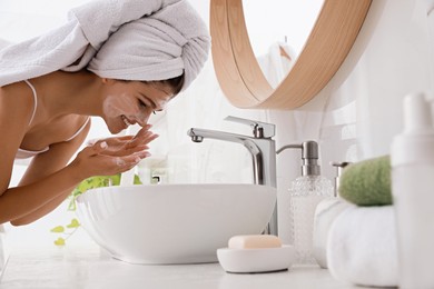 Photo of Beautiful teenage girl washing face with cleansing foam in bathroom. Skin care cosmetic