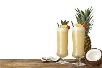 Tasty Pina Colada cocktail and ingredients on wooden table against white background, space for text