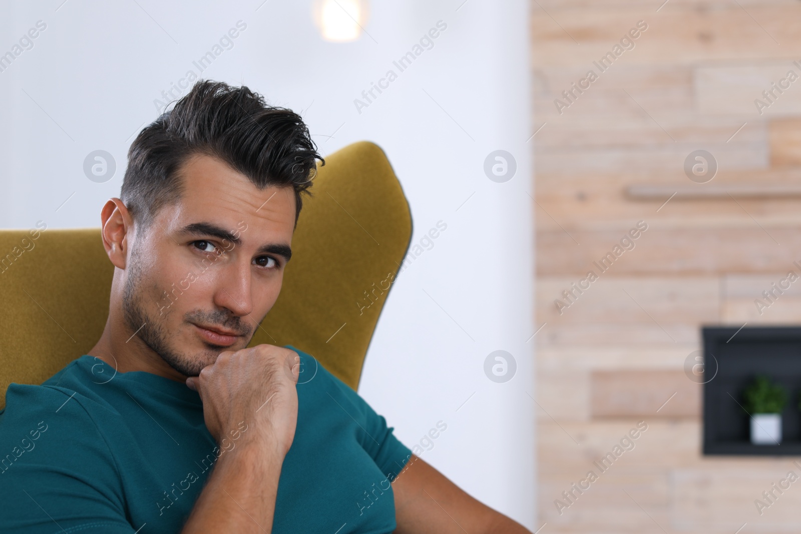 Photo of Portrait of handsome young man sitting in armchair at home