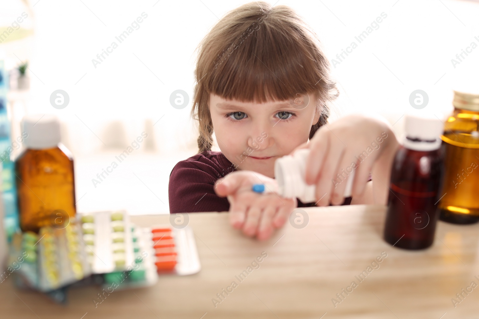 Photo of Little child taking pills from shelf at home. Danger of medicament intoxication