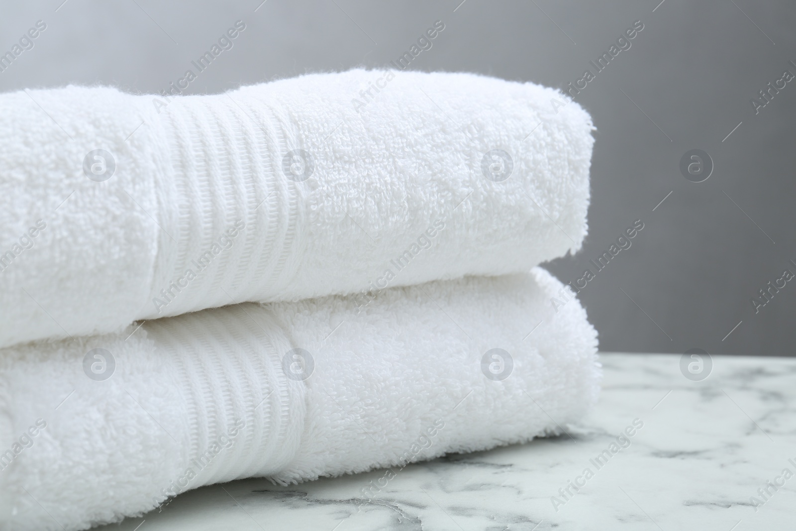 Photo of Folded terry towels on white marble table, closeup