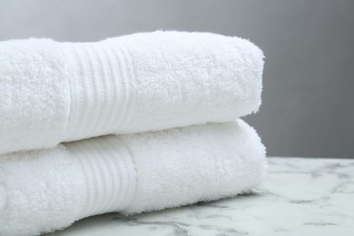 Photo of Folded terry towels on white marble table, closeup