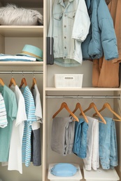 Photo of Stylish clothes, accessories and home stuff in wardrobe closet