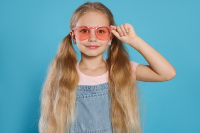 Photo of Girl in pink sunglasses on light blue background