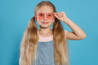 Girl in pink sunglasses on light blue background