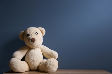 Photo of Abandoned teddy bear on table against dark background. Time to visit child psychologist