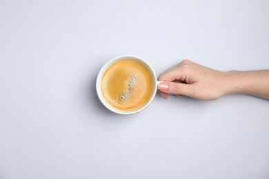 Woman with cup of coffee on white background, top view