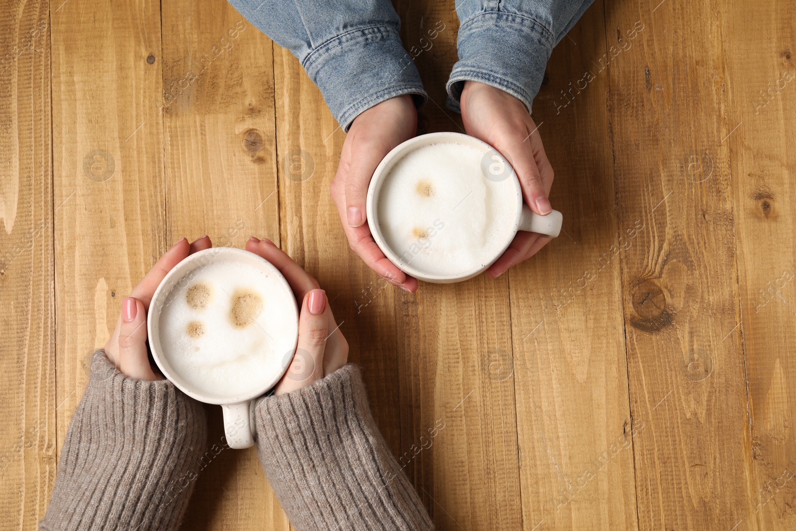 Photo of Women having coffee break at wooden table, top view