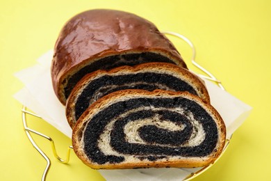 Photo of Slices of poppy seed roll on yellow background, closeup. Tasty cake