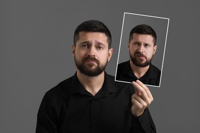 Man holding photo portrait with his facial expression on grey background. Personality crisis, different emotions