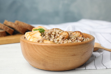 Photo of Tasty buckwheat porridge with meat on white wooden table