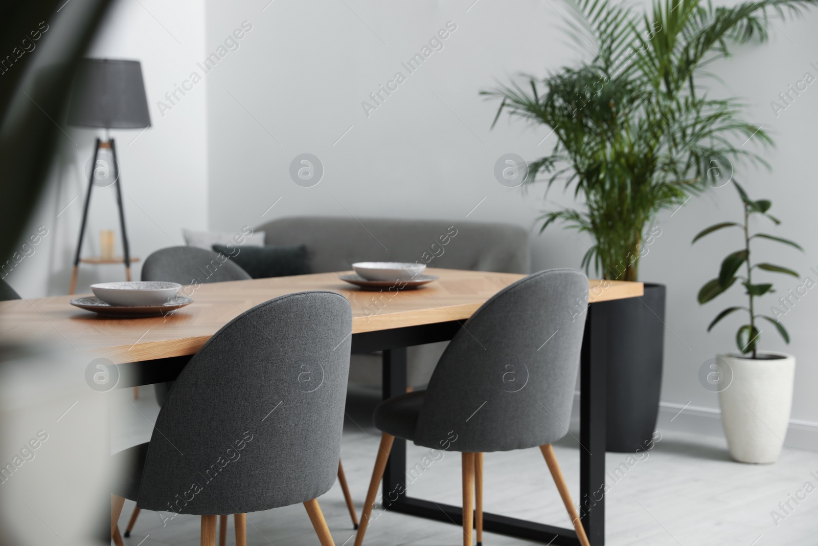 Photo of Stylish wooden table and chairs in light room. Modern interior design