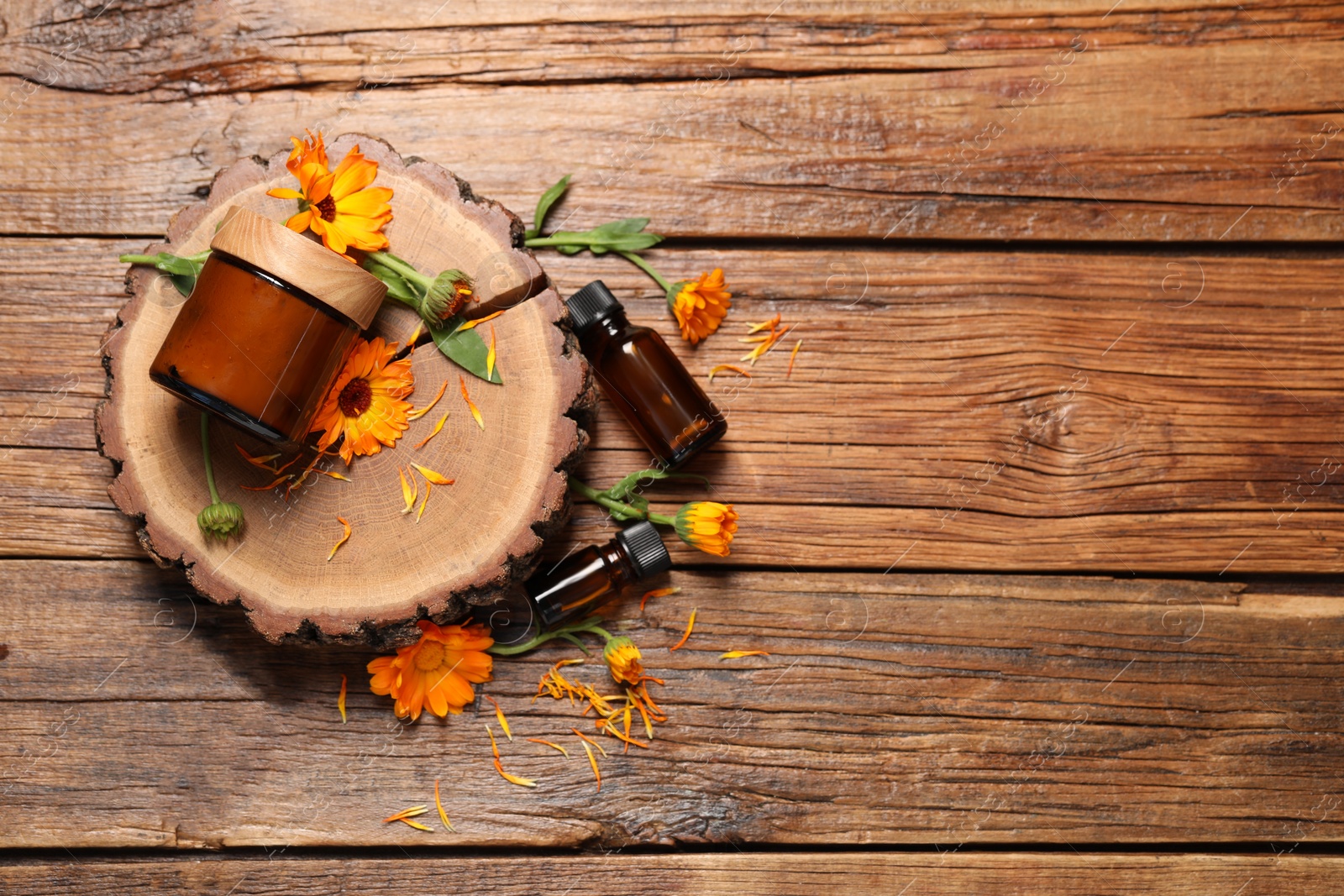 Photo of Different cosmetic products and beautiful calendula flowers on wooden table, flat lay. Space for text