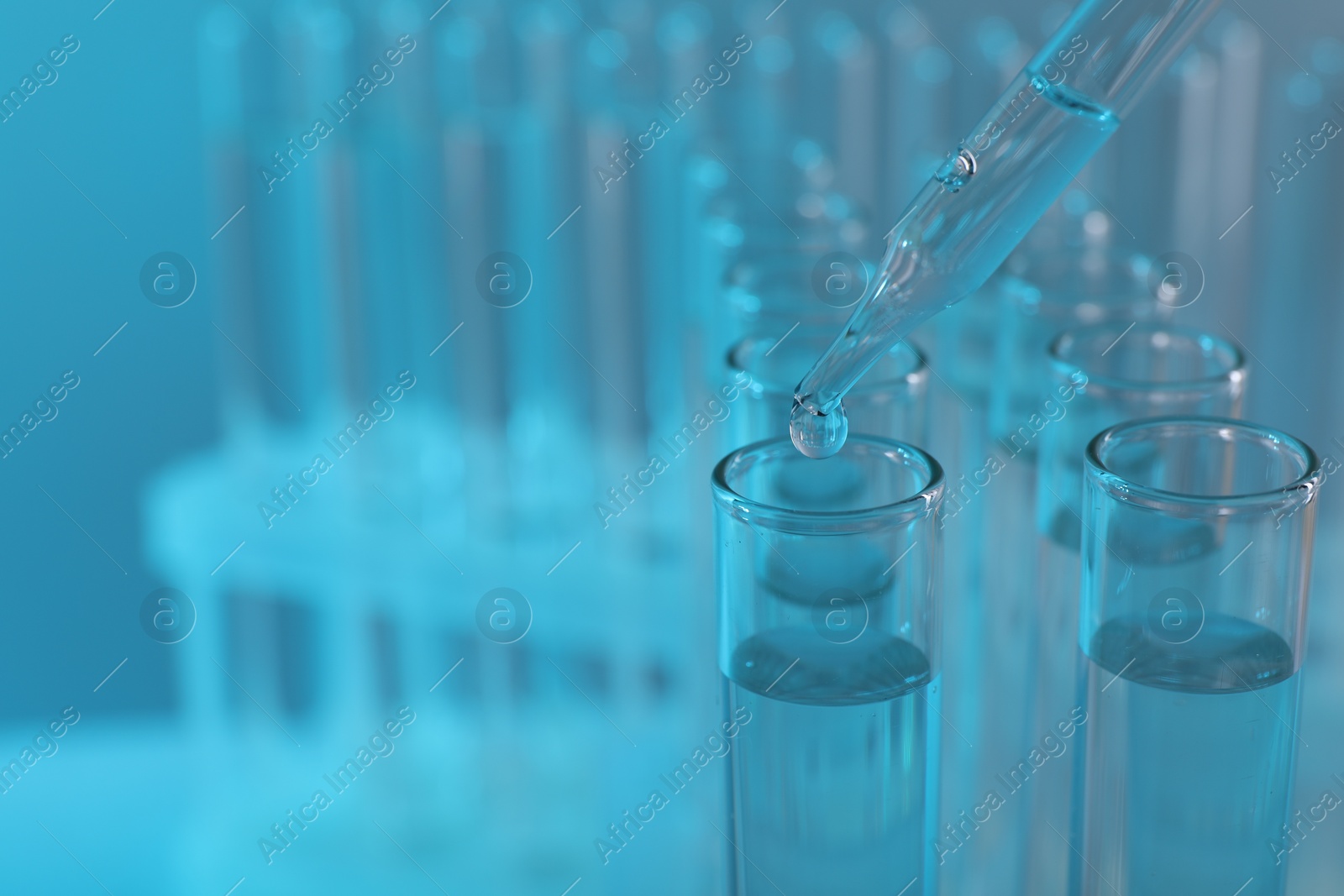 Photo of Laboratory analysis. Dripping liquid from pipette into glass test tube on light blue background, closeup and space for text