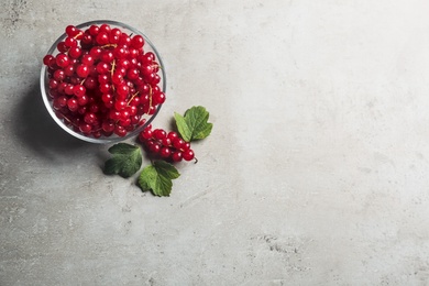 Photo of Delicious red currants and leaves on light grey table, flat lay. Space for text
