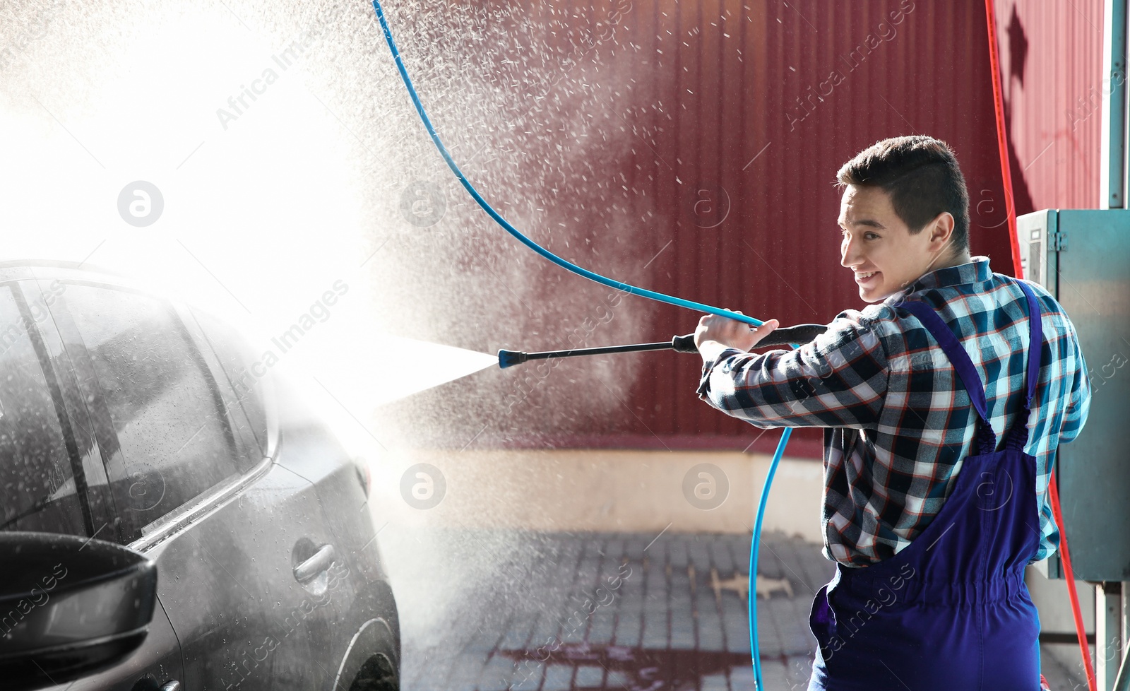 Photo of Worker cleaning automobile with high pressure water jet at car wash