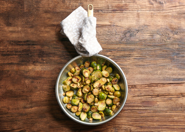 Photo of Delicious roasted brussels sprouts with peanuts on wooden table, top view