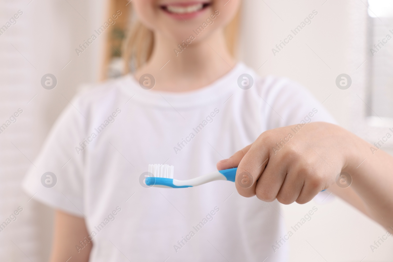 Photo of Little girl holding plastic toothbrush, closeup view