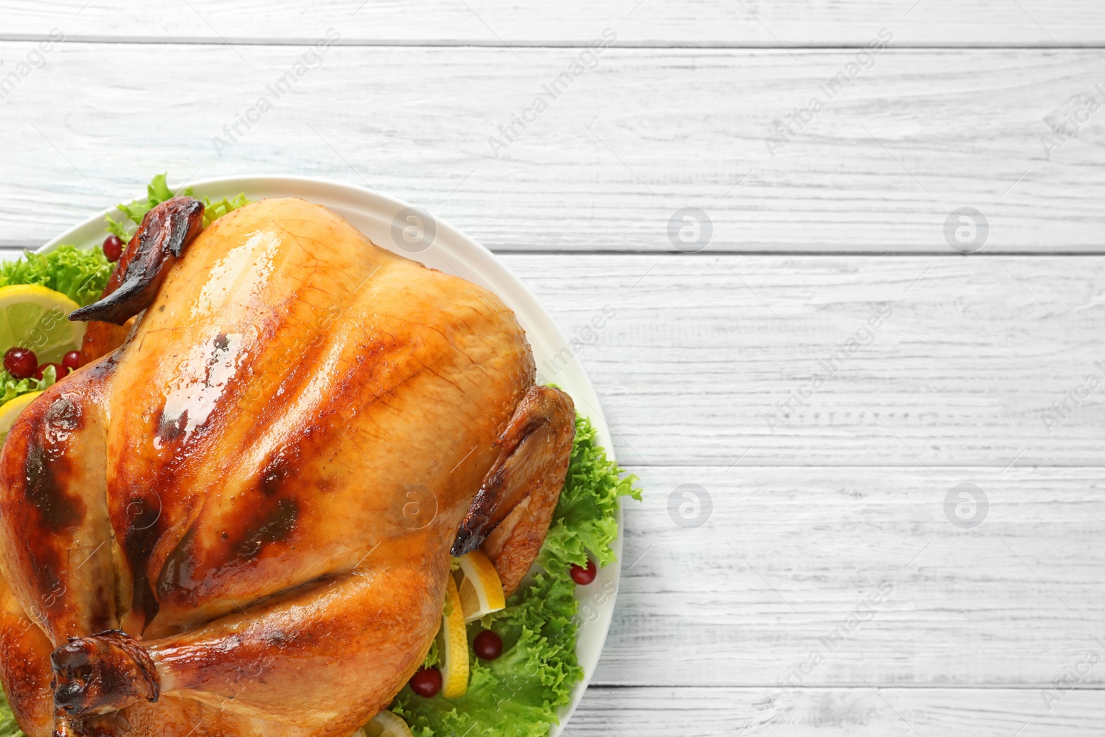 Photo of Delicious roasted turkey on wooden table, top view. Space for text
