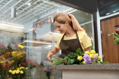 Photo of Female florist making beautiful bouquet in flower shop