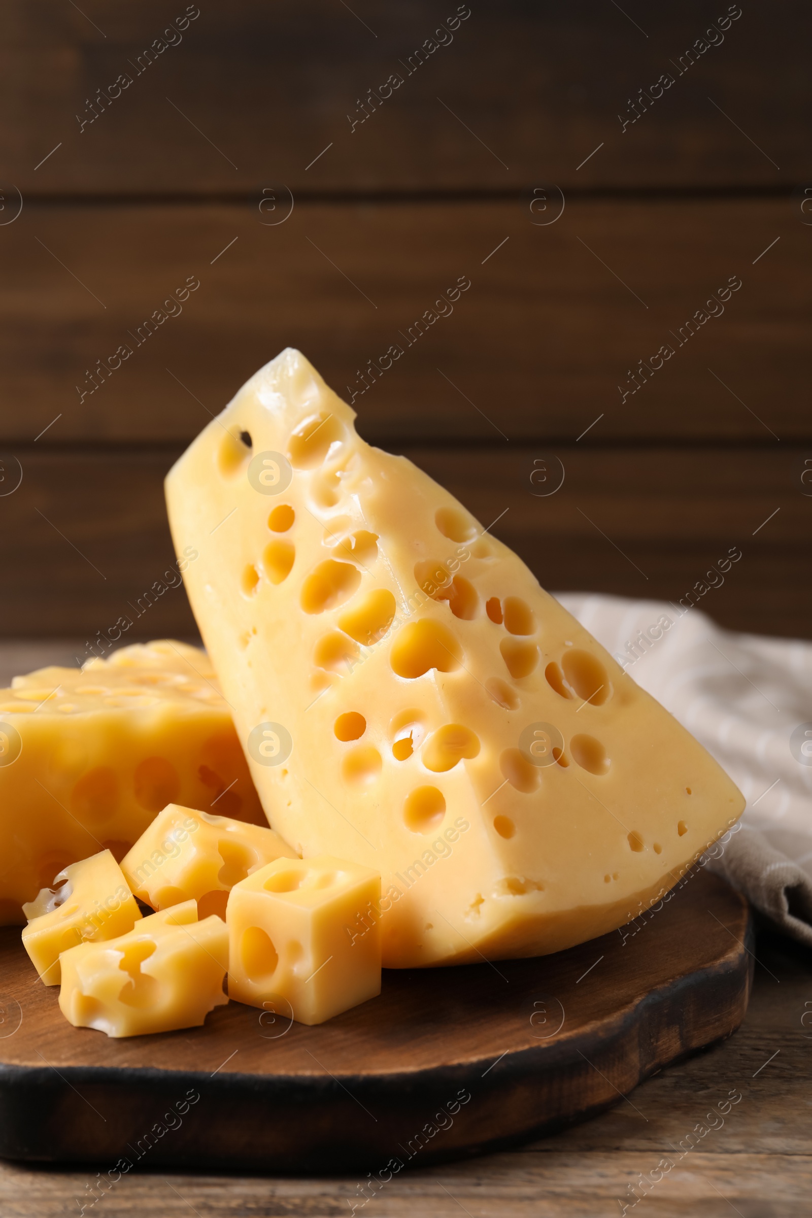 Photo of Pieces of delicious cheese on wooden table, closeup